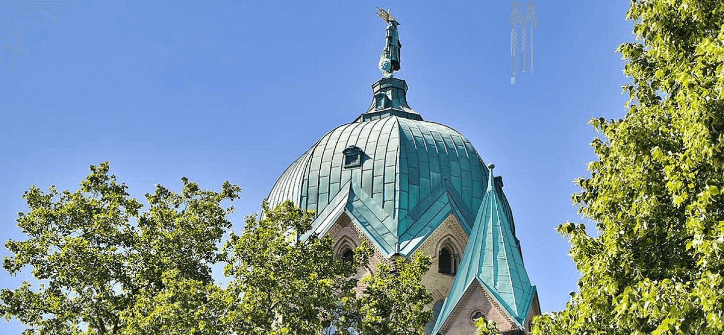 Kuppel des Quirinus-Münsters in Neuss umgeben von Bäumen – kulturelles Wahrzeichen für ein Duales Studium Soziale Arbeit in Neuss an der CBS.