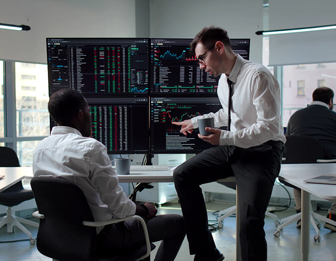 Risk Analyst analysiert Finanz- und Marktdaten vor mehreren Monitoren und bespricht Risiken. Visualisierung der Karrierechancen nach dem  Data Analytics an der  im Bereich Risikoanalyse und Finanzanalyse.