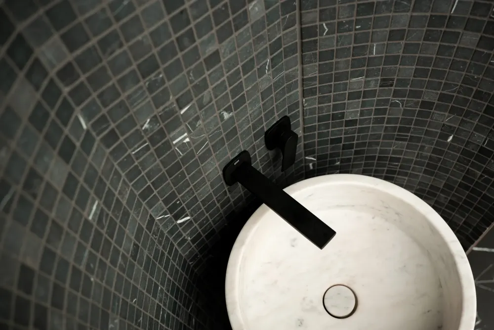 Marble basin against dark mosaic tile