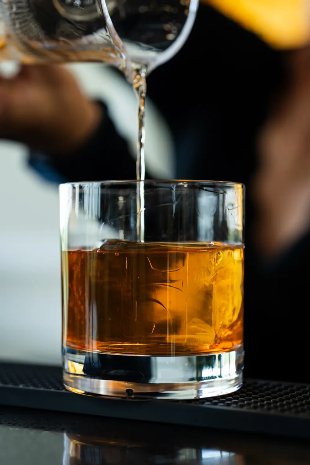 An amber cocktail poured over ice at the bar