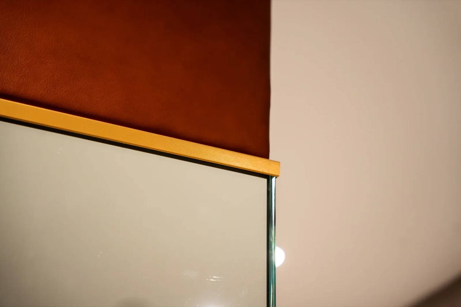 Terracotta leather panel meeting brass and glass