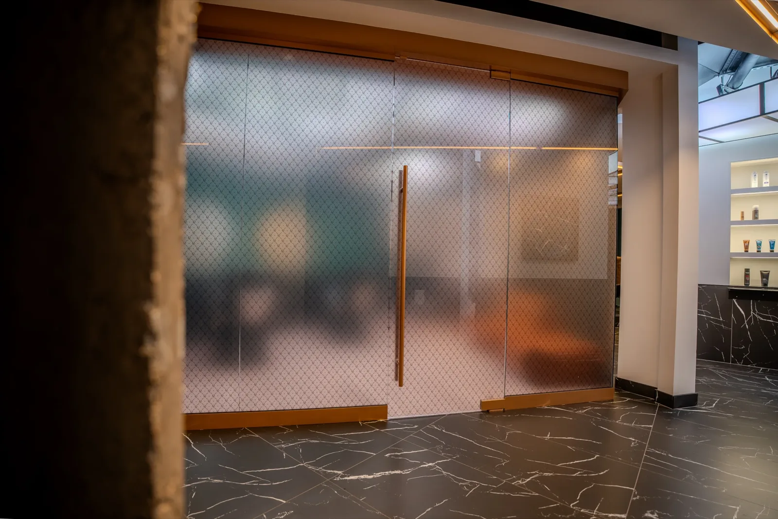 The frosted glass doors and brass handle at the entrance