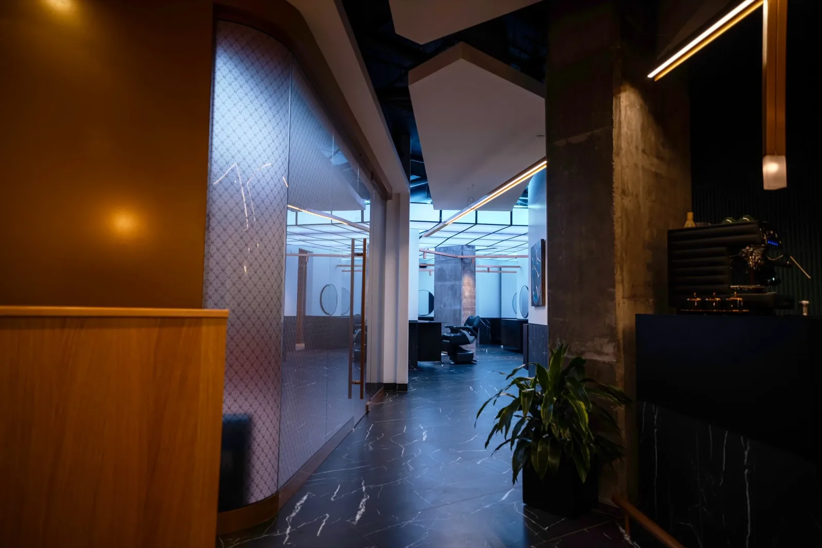 Arrival corridor at Gallantier, amber reception counter and frosted glass partition