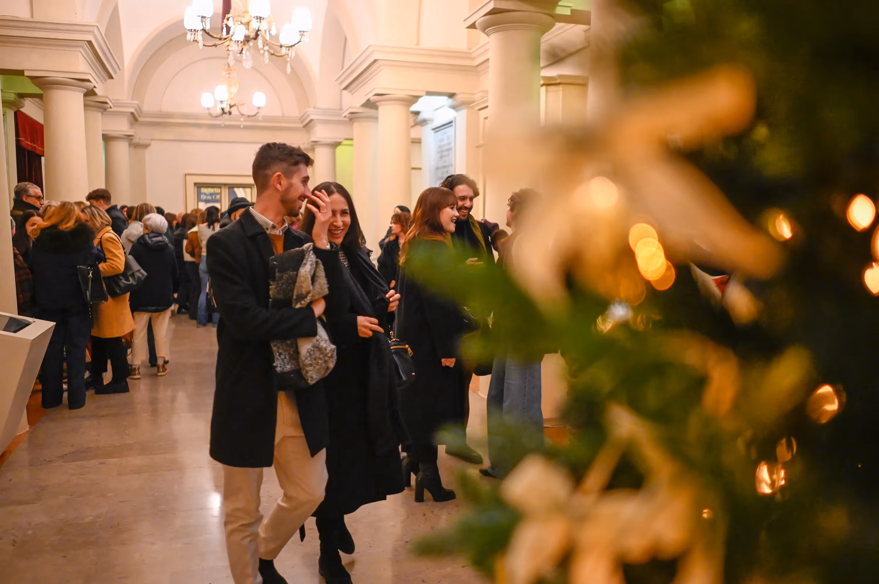 Ospiti sorridenti al Festival di Spoleto in elegante sala con lampadari