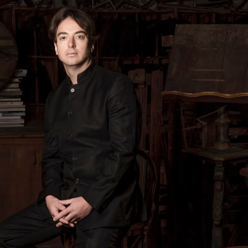 Portrait for Festival dei Due Mondi, man in black seated against antique background