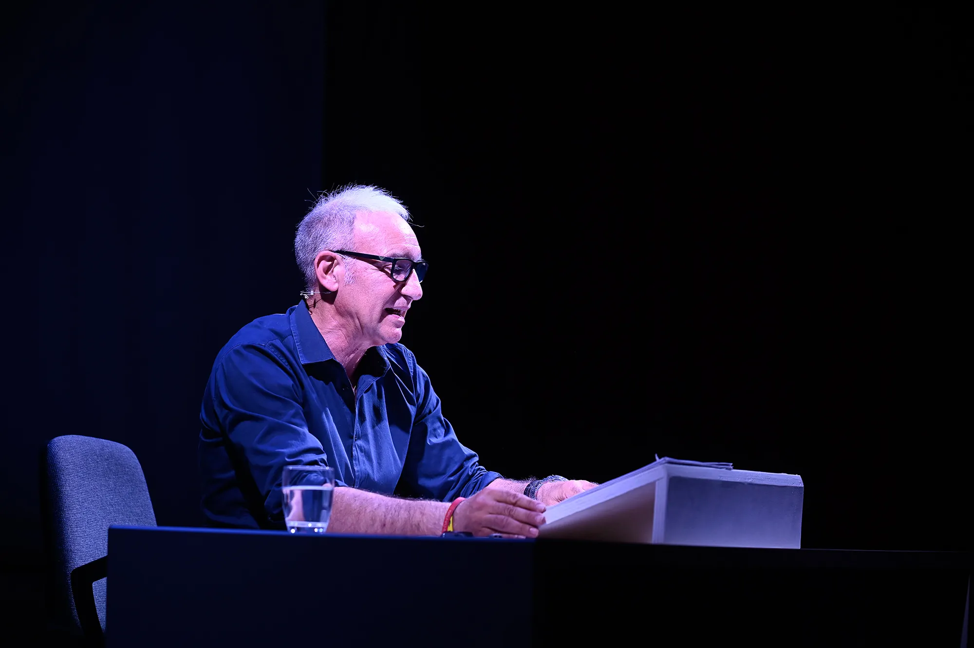 Ospite anziano sul palco durante il Festival di Spoleto, seduto e concentrato