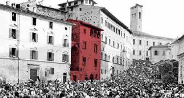 Crowded Festival di Spoleto street with vibrant red building amid black-and-white scene