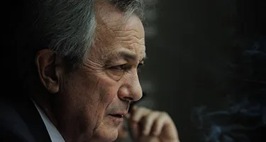 Contemplative elder at Festival di Spoleto, deep in thought with shadowy background