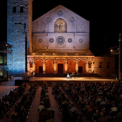 Spettacolo serale al Festival di Spoleto, cattedrale illuminata gremita di pubblico