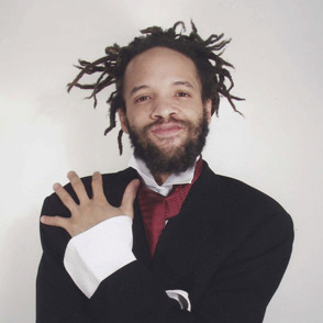 Artista sorridente al Festival di Spoleto con dreadlock e giacca nera