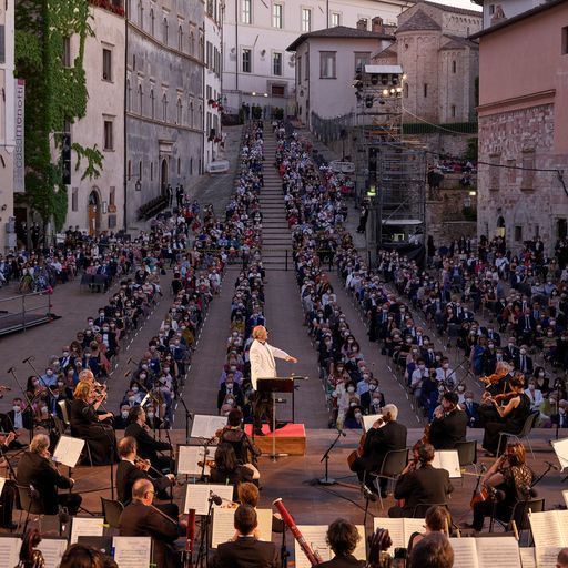 Orchestra sinfonica sul palco durante il Festival di Spoleto, piazza gremita di spettatori