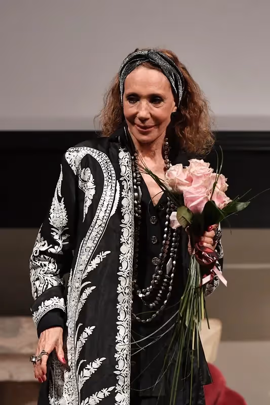 Performer with pink roses at Festival di Spoleto stage wearing ornate black coat