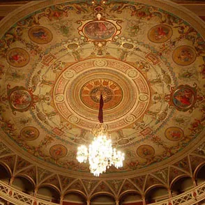 Ornate ceiling of historic theater at Festival di Spoleto, illuminated by chandelier