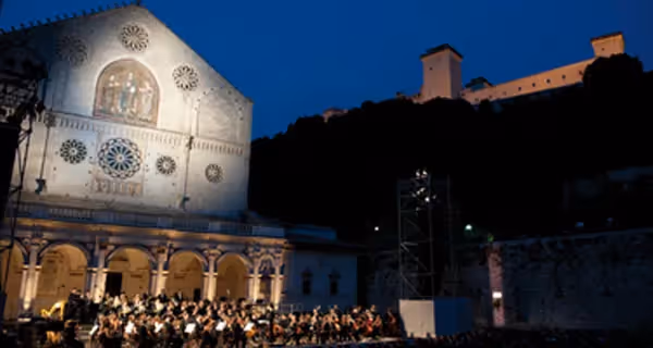 Concerto notturno al Festival di Spoleto, orchestra davanti a cattedrale illuminata