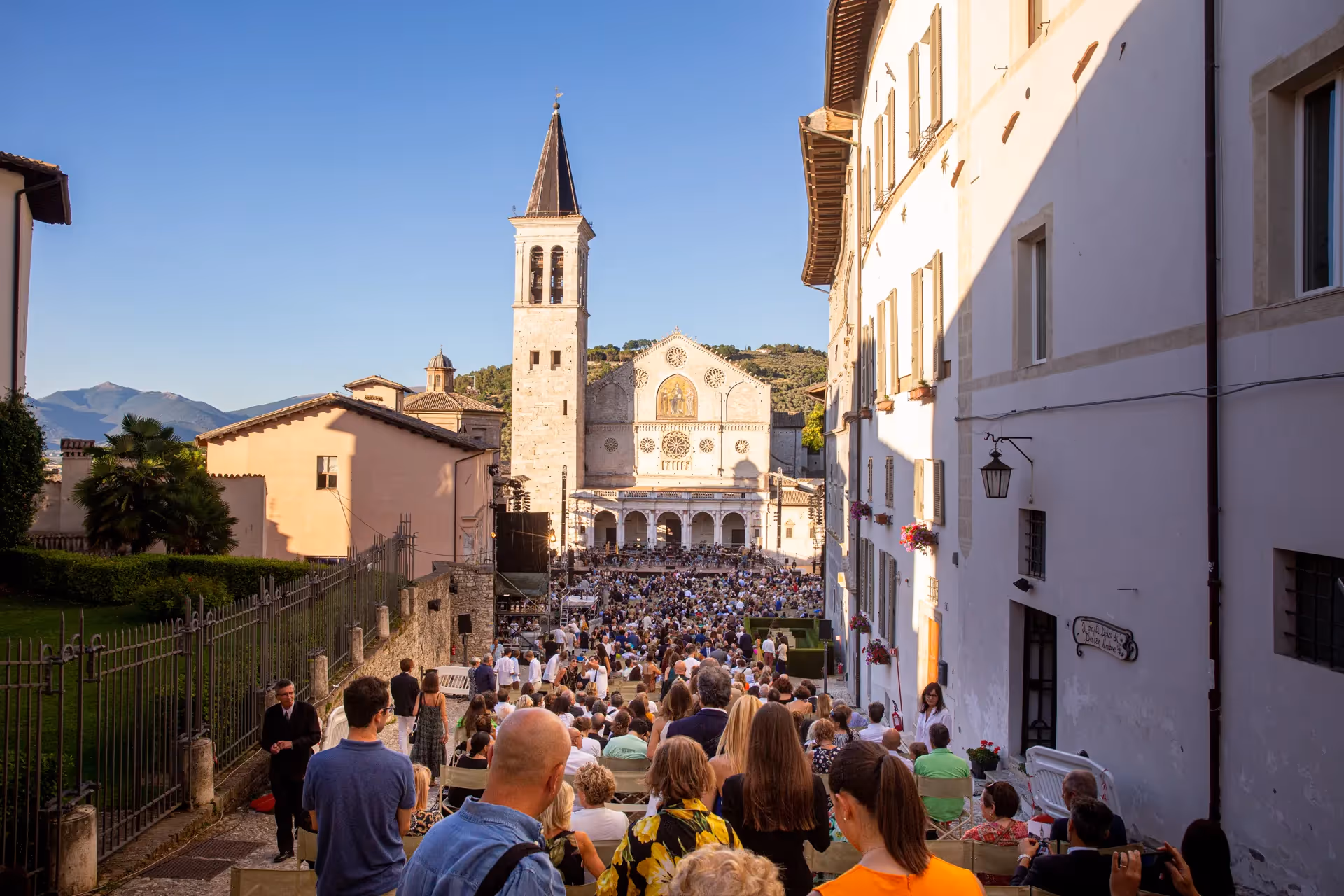 Folla al Festival di Spoleto davanti alla cattedrale con montagne sullo sfondo