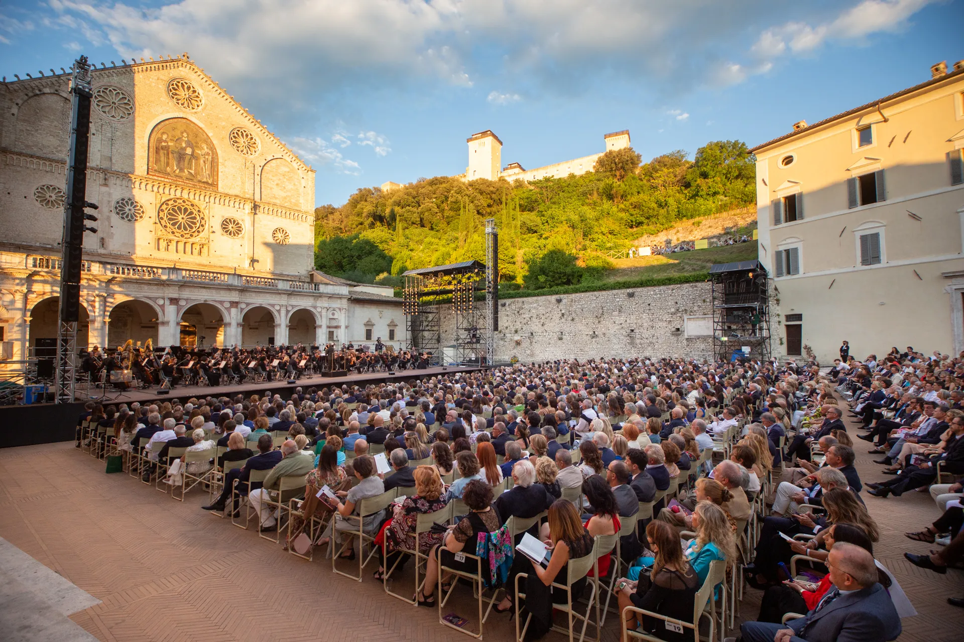 Packed concert at Festival di Spoleto with orchestra performing in historic square