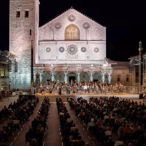 Concerto serale al Festival di Spoleto, orchestra davanti alla cattedrale illuminata