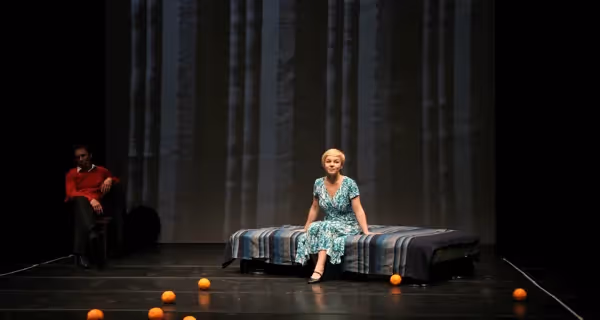 Attrice sul palco durante il Festival di Spoleto, seduta con arance sparse