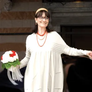 Woman in white dress at Festival di Spoleto, holding festive floral arrangement