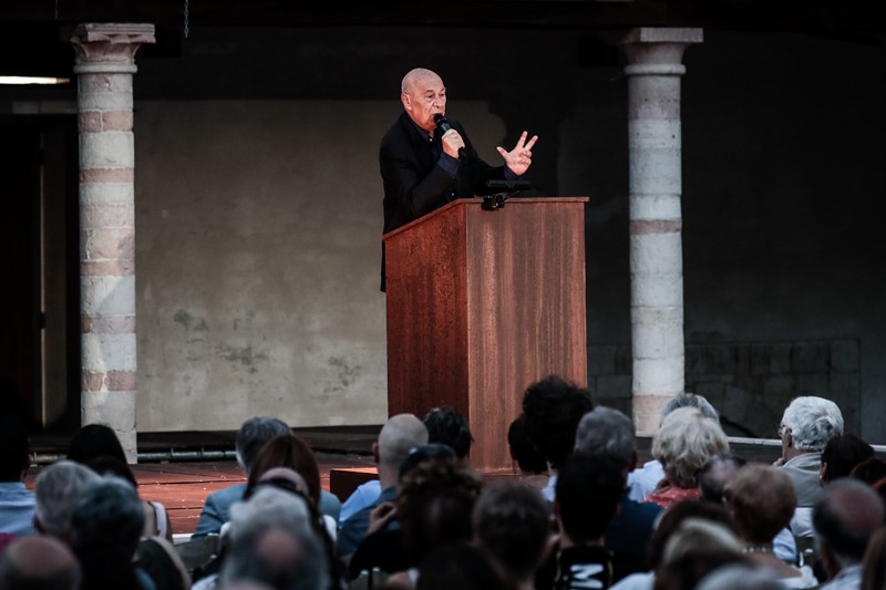 Relatore sul palco durante il Festival di Spoleto, circondato da colonne storiche