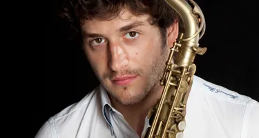 Saxophone musician poses at Festival di Spoleto, wearing white shirt