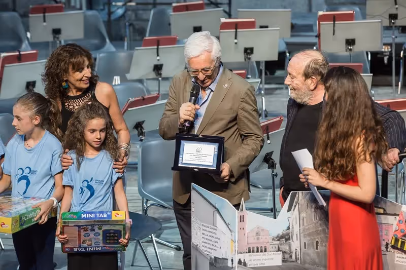 Festival di Spoleto award ceremony with recipients and children in auditorium