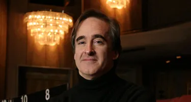Artist at Festival di Spoleto, seated beneath elegant chandelier in warm lighting
