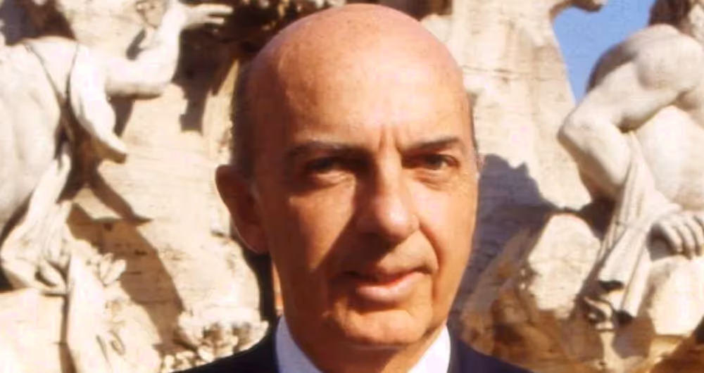 Festival di Spoleto founder Giancarlo Menotti standing before sculptural backdrop