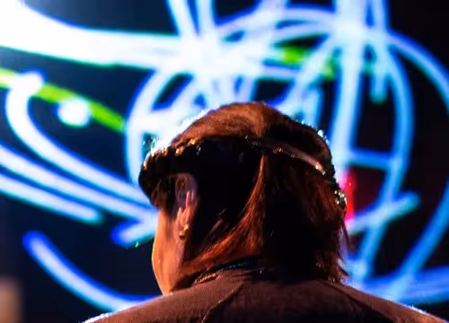 Spettatore al Festival di Spoleto con luci al neon sullo sfondo astratto