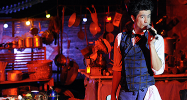 Performer sul palco al Festival di Spoleto, atmosfera suggestiva e colorata