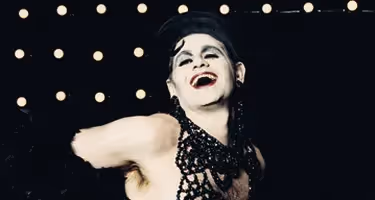 Performer in black beaded top laughing at Festival di Spoleto event