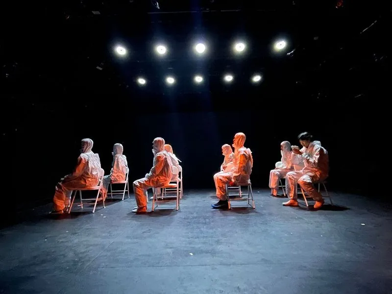 Festival di Spoleto performance with performers in orange and white under dramatic stage lighting