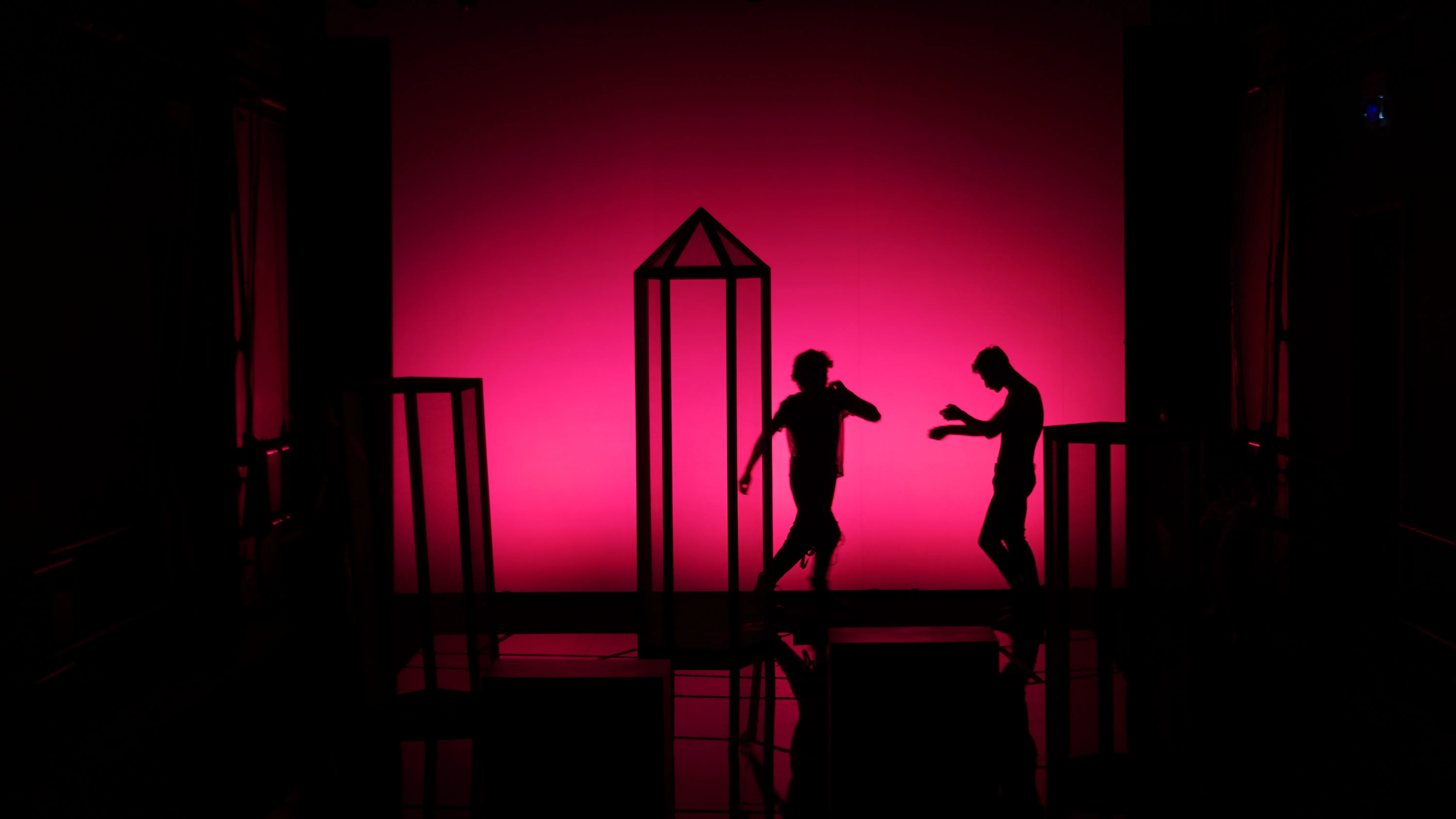 Sagome di danzatori sul palco del Festival di Spoleto con sfondo rosa intenso