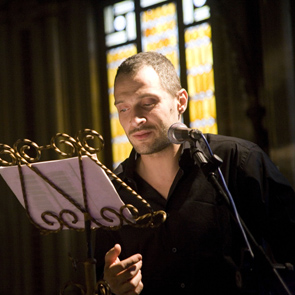 Artist performing at Festival di Spoleto, reading from music stand near stained glass