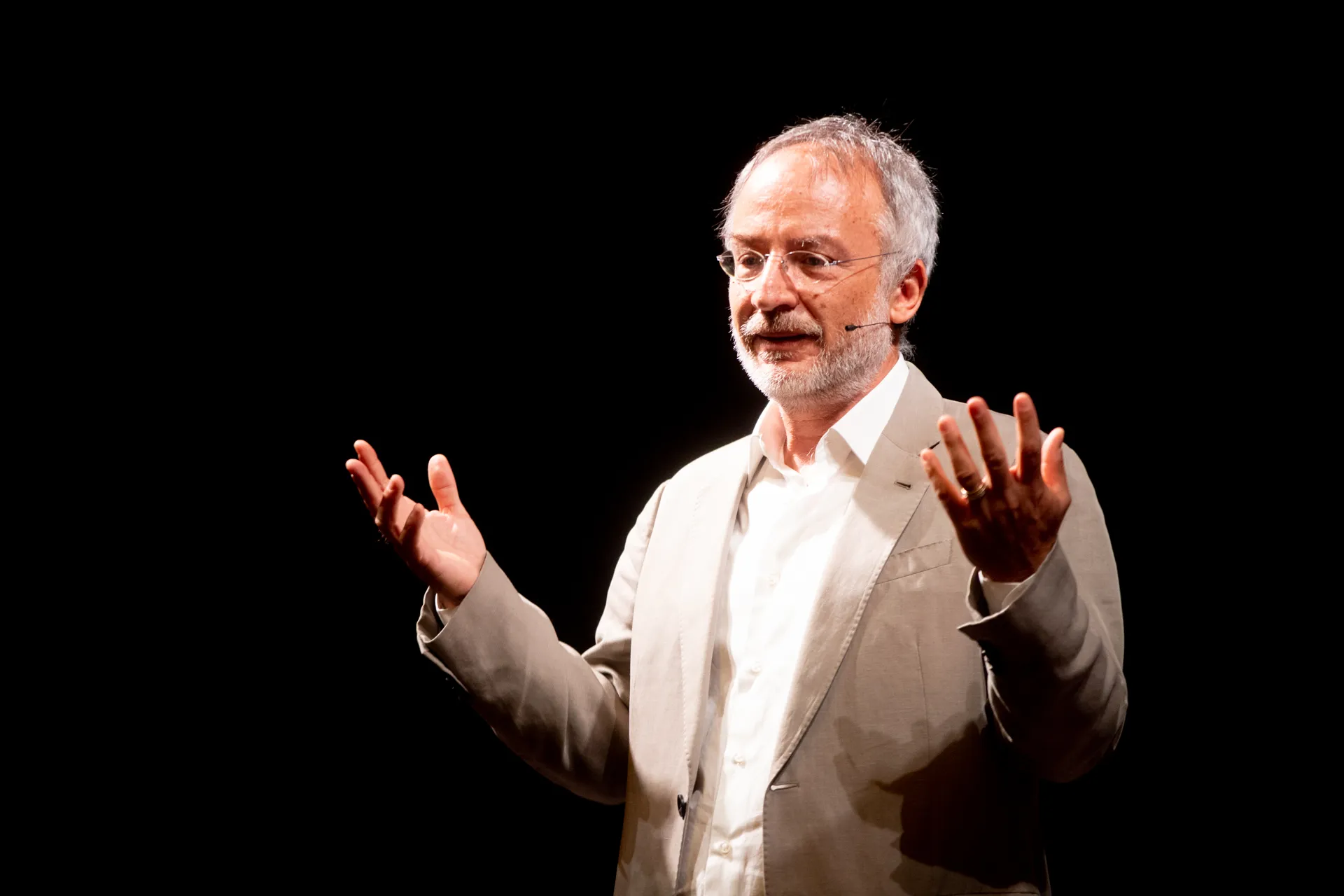 Speaker presenting at Festival di Spoleto, gesturing on dark stage
