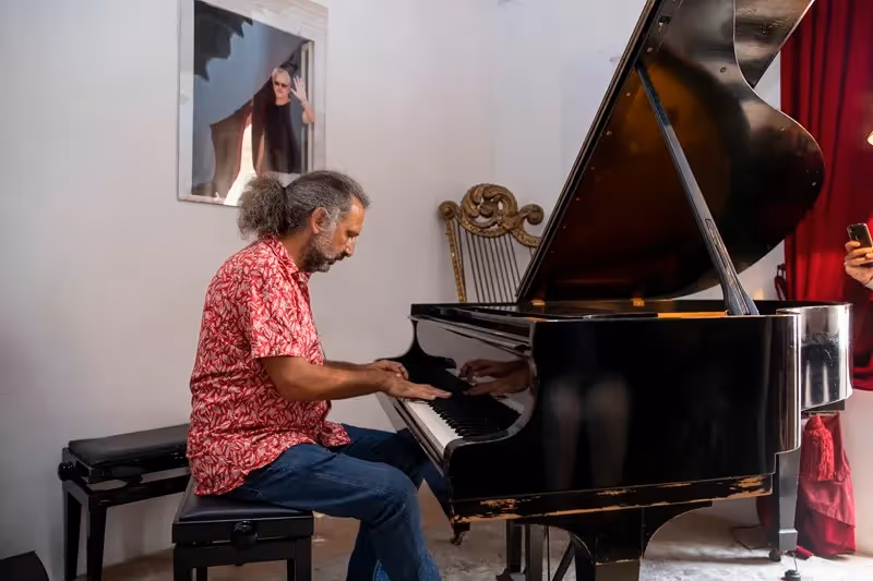 Pianist performs at Festival di Spoleto, playing grand piano with red curtain backdrop