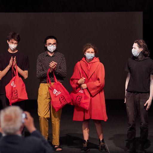 Quattro performer con maschere al Festival di Spoleto, borse rosse in mano