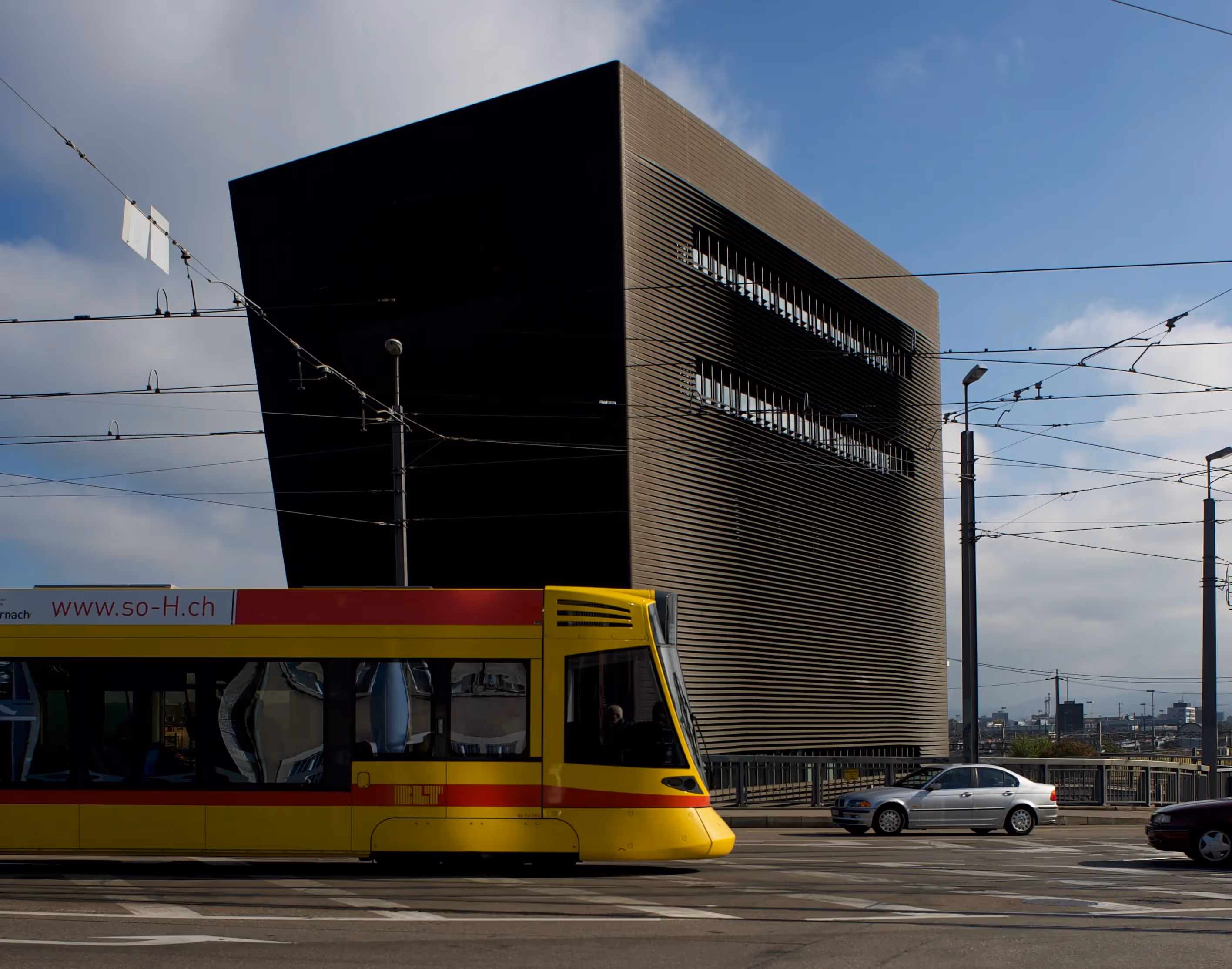 Tram giallo accanto a un edificio moderno con Festival di Spoleto sullo sfondo
