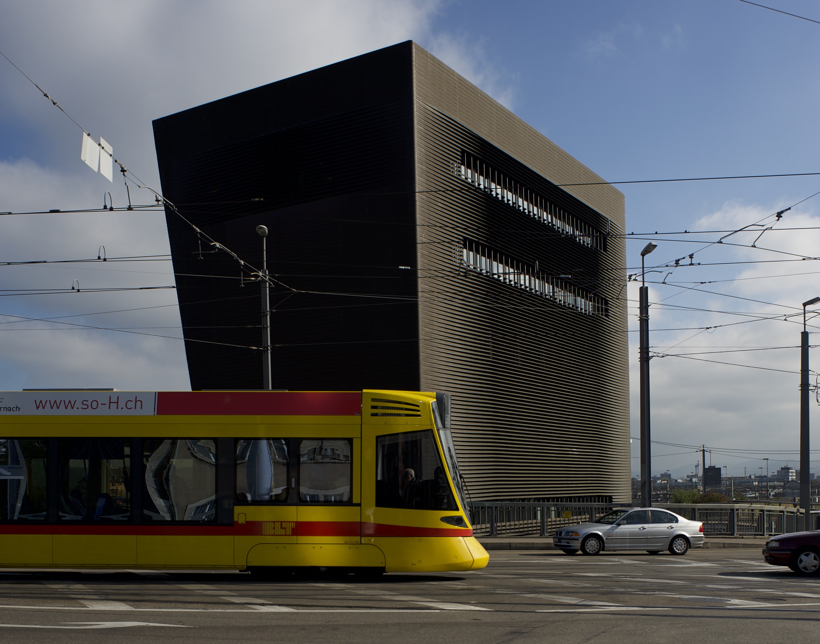 Modern urban scene with yellow tram passing black and gold architectural building