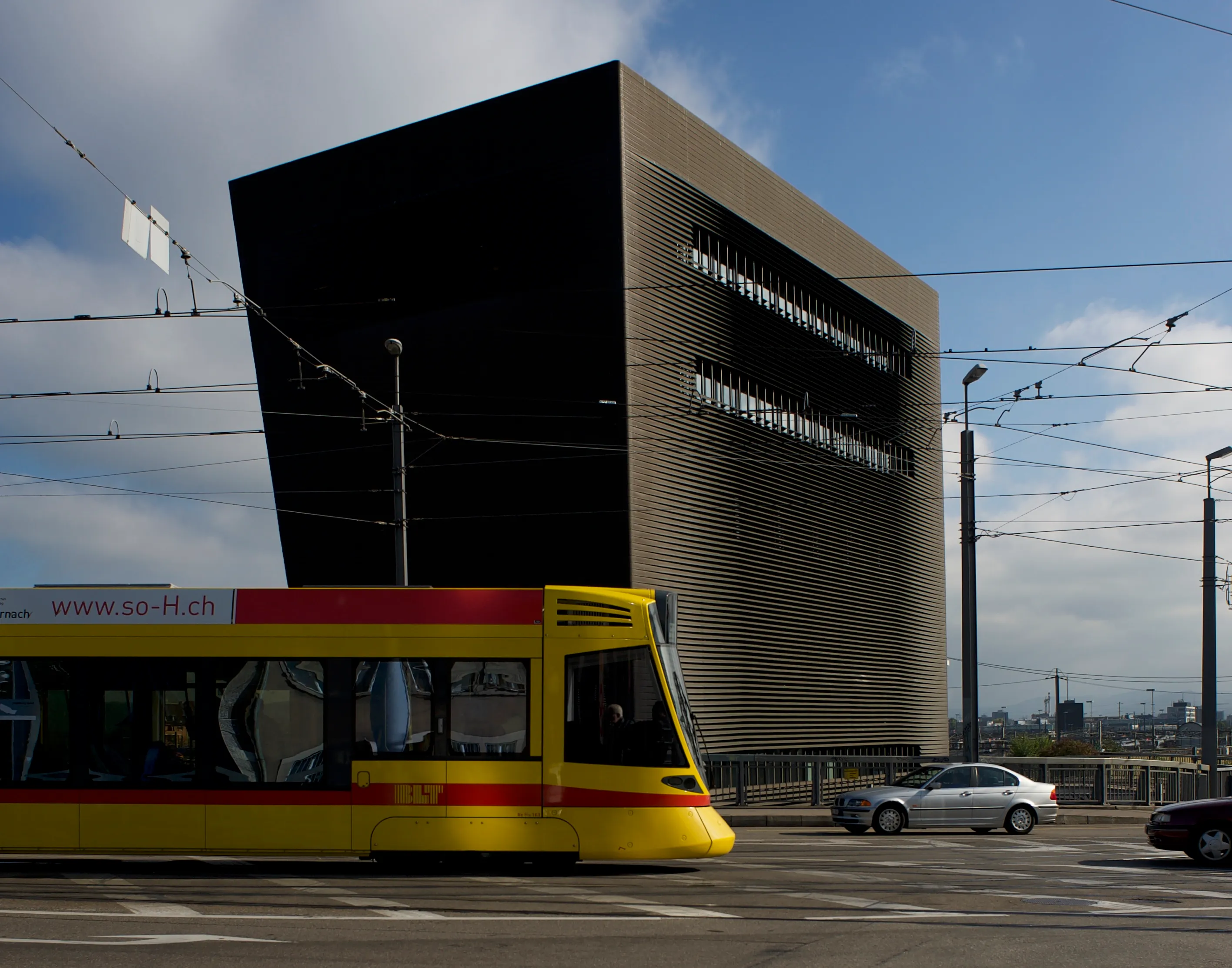 Modern urban scene with yellow tram passing black and gold architectural building