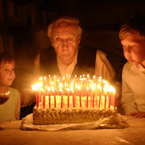 Festa di Spoleto: anziano soffia candeline con giovani accanto alla torta illuminata