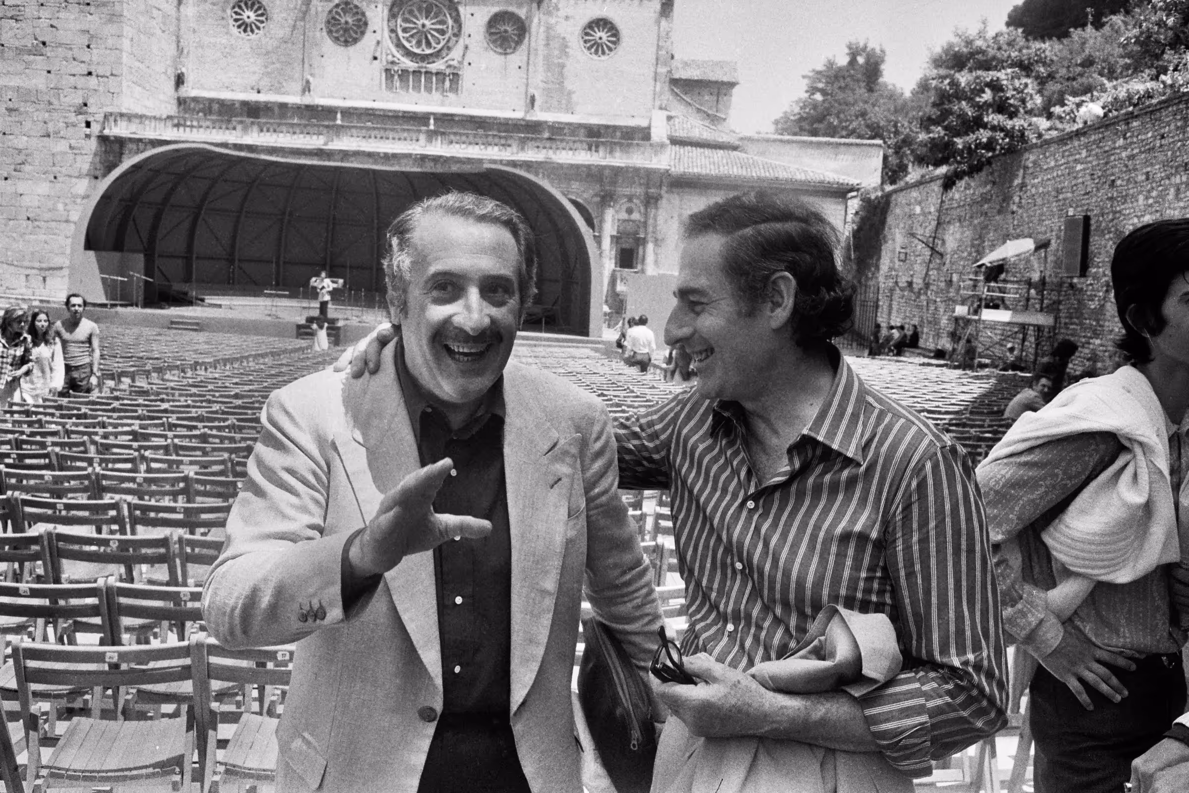 Two men laughing at Festival di Spoleto, empty theater in background