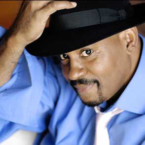 Festival di Spoleto performer in blue shirt and black hat poses dramatically