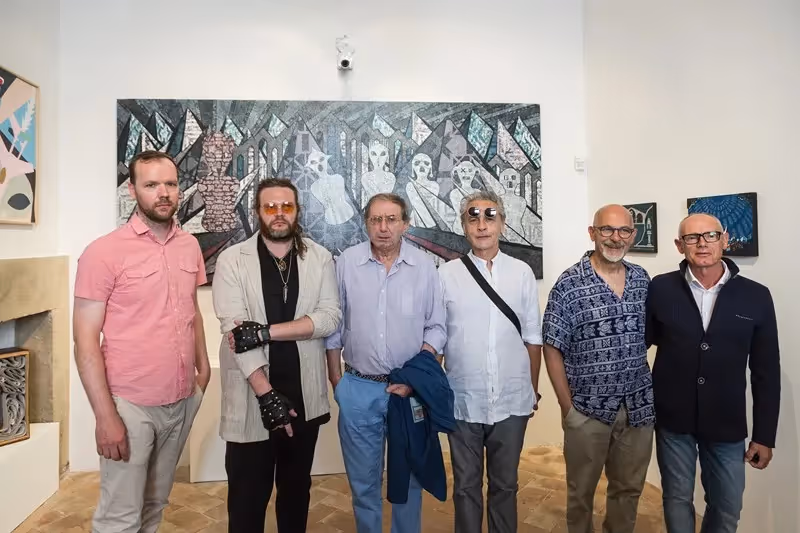 Sei artisti al Festival di Spoleto, posa davanti a un'opera d'arte astratta