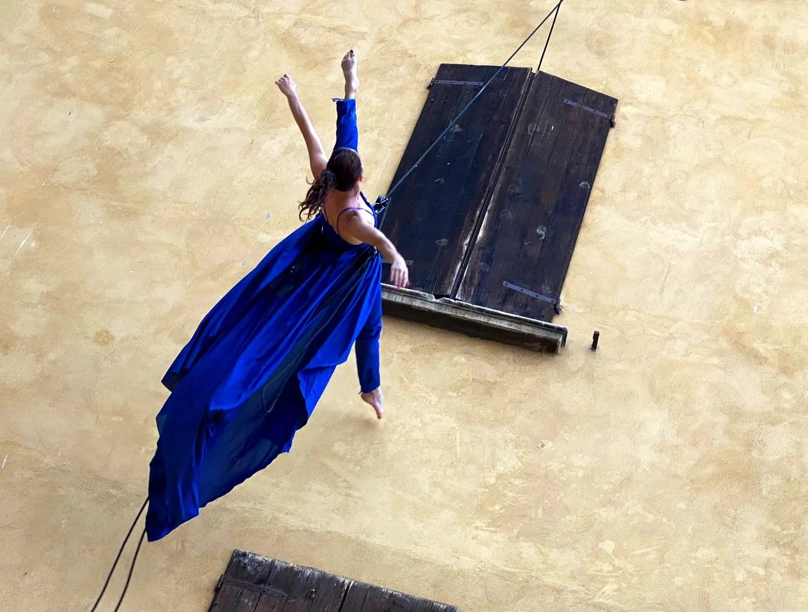 Performer in blu al Festival di Spoleto, movimento dinamico vicino a vecchia finestra