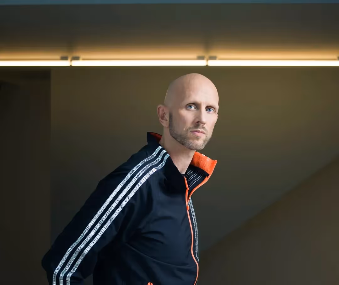 Pensive bald artist portrait in black and orange athletic jacket