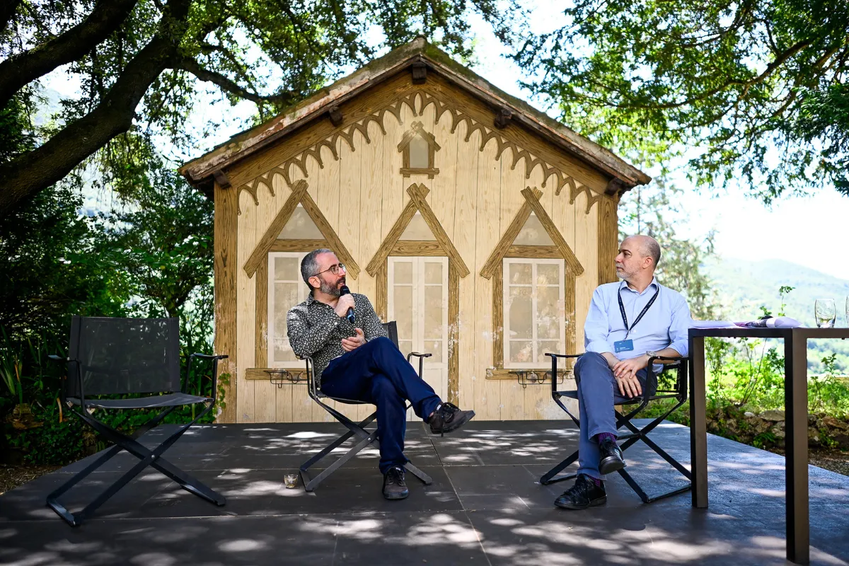 Video Festival di Spoleto: due uomini in conversazione davanti a una casetta in legno