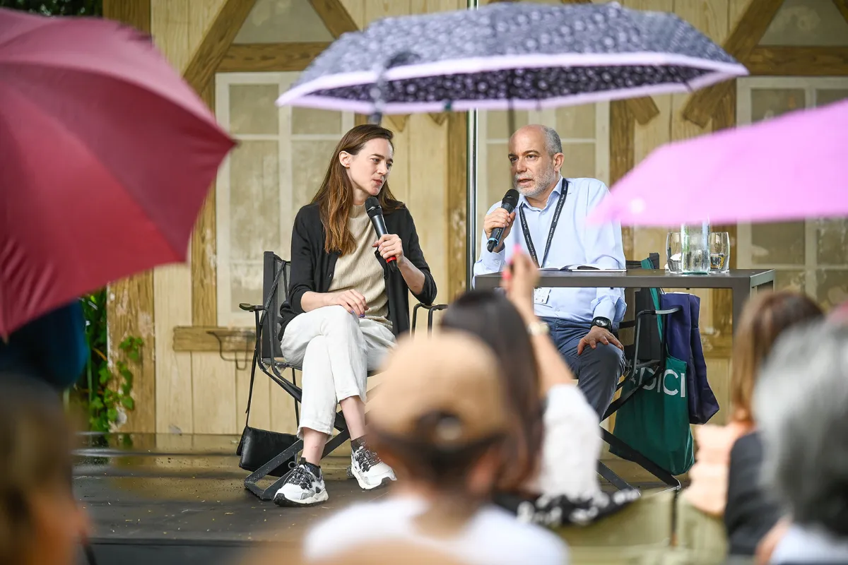 Video Festival di Spoleto: due relatori sotto ombrelli durante un incontro pubblico