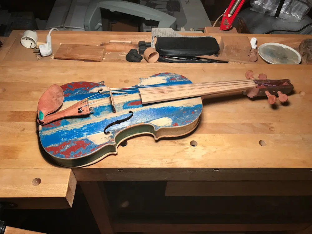 Colorful violin at Festival di Spoleto, resting on wooden workbench