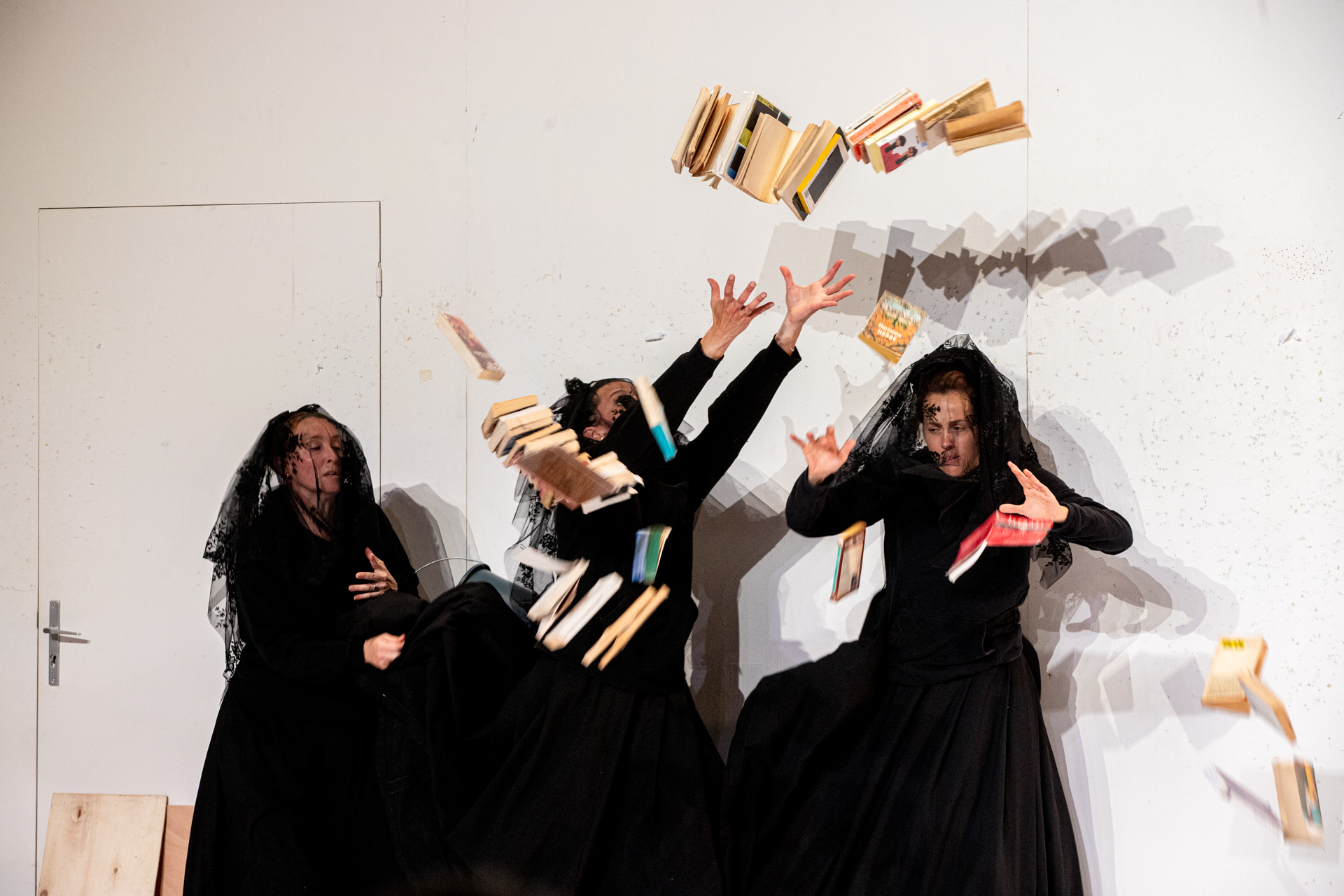 Festival di Spoleto performance: Three black-clad figures throwing books dramatically